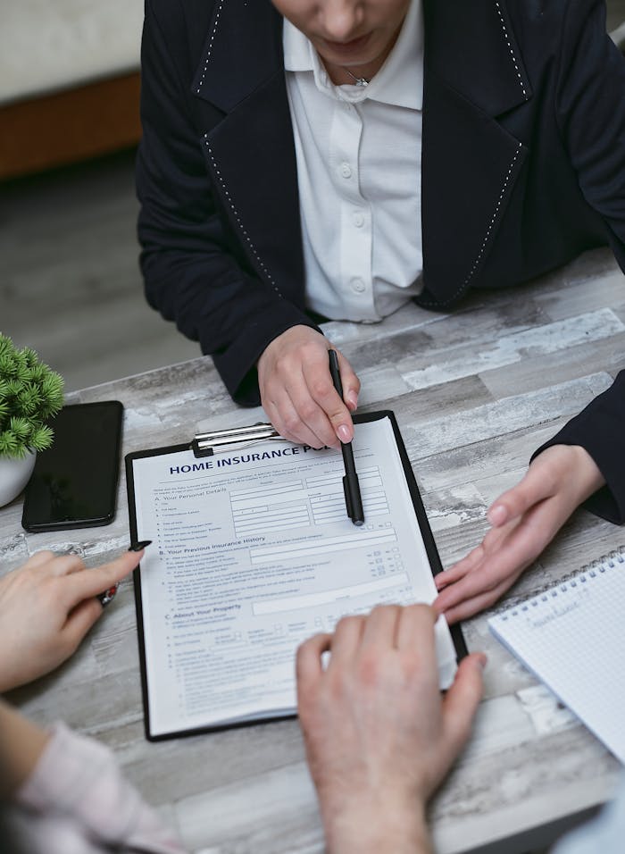 gallery-02 An agent and clients discussing paperwork for home insurance at a meeting table.