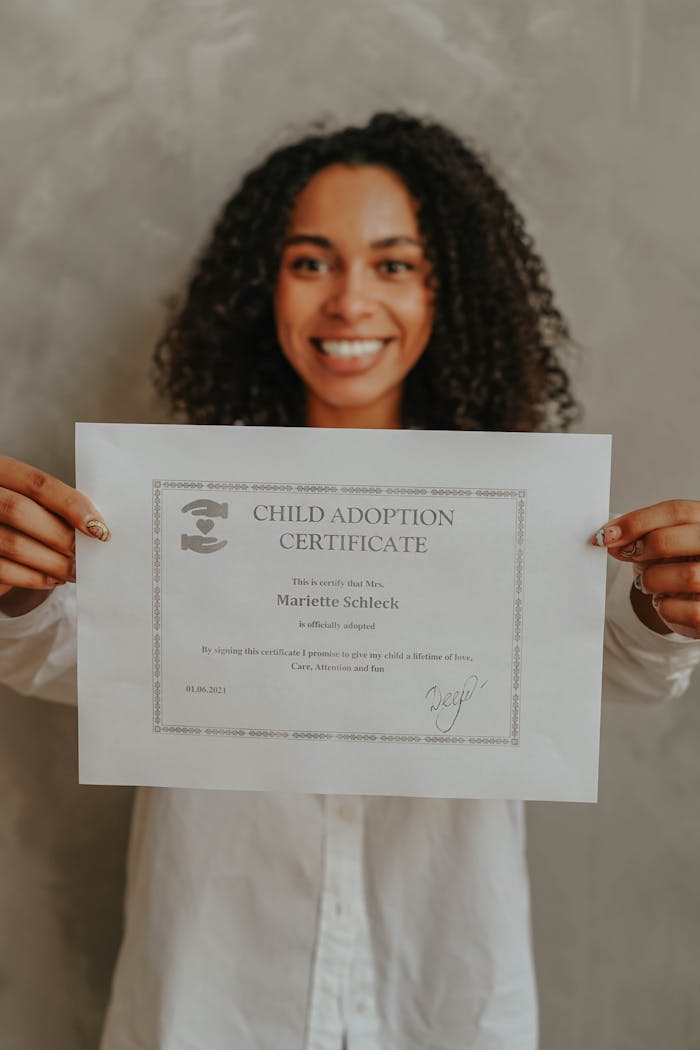 gallery-04 A joyful woman proudly displays her child adoption certificate indoors.
